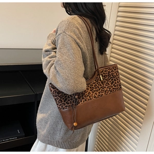 Detail of leopard print tote bag with wooden bead tassel and elegant leather stitching