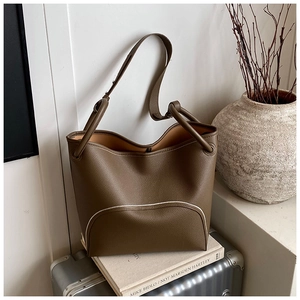Detail of olive green pebbled leather tote with white stitching on a silver suitcase