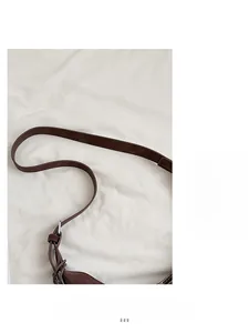 Detail of dark brown leather strap with silver buckle and fine stitching on tote bag