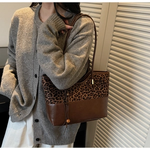 Detail of leopard print tote bag with brown leather base and wooden bead tassel