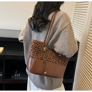 Detail of leopard print tote bag with brown leather straps and wooden bead charm
