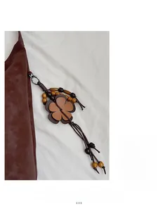 Detail of dark brown matte tote bag featuring vintage wooden bead and leather floral charms