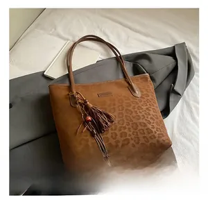 Detail of leopard embossed texture on brown suede tote bag with stylish tassel pendant