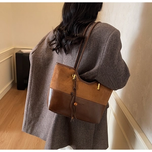 Detail of retro contrast tote bag with suede texture and wooden bead charm on shoulder
