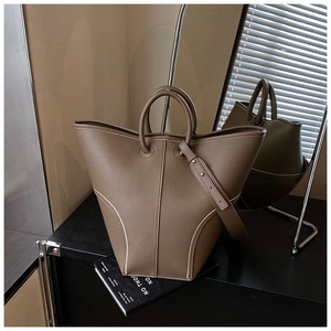 Detailed view of brown leather bucket bag with contrast stitching and wide strap