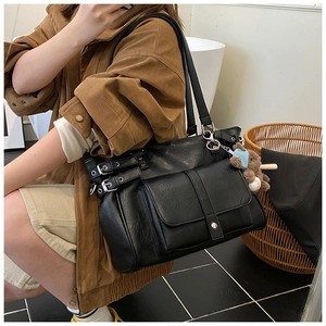 Detailed shot of large black faux leather tote bag with pocket and bear pendant detail
