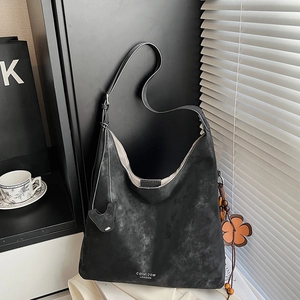 Detail of vintage black leather tote bag with floral charm and adjustable shoulder strap