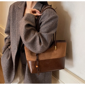 Close-up of contrast stitching tote bag with suede panel and wooden bead tassel