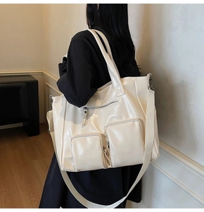 Detail of creamy white faux leather tote bag showing large capacity and front zip pockets