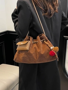 Vintage brown suede bucket bag with drawstring and decorative pom-poms for daily use