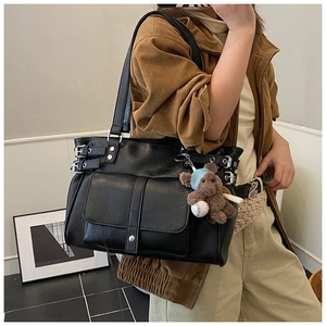 Detail of black tote bag with metal buckles and a cute plush bear charm for daily use