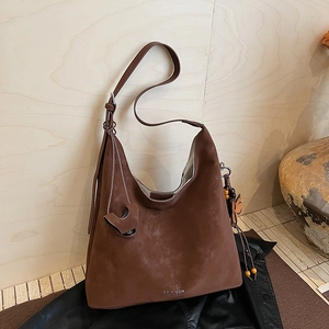 Detail of dark brown faux suede tote bag with leaf charm and adjustable shoulder strap