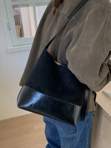 Retro large capacity black tote bag with suede splicing worn by model in cozy interior