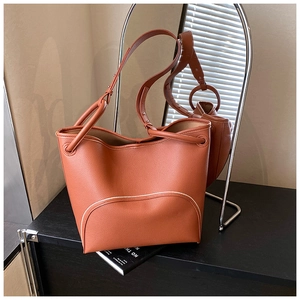 Close-up of caramel pebbled leather bucket bag featuring white contrast stitching details