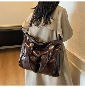 Detail of a large vintage brown PU leather tote bag with functional front zippers and strap