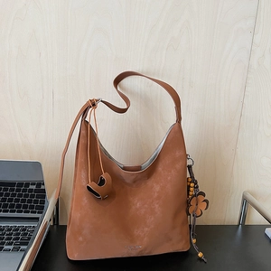 Detail of vintage brown suede hobo bag with wood bead tassel and logo embossing