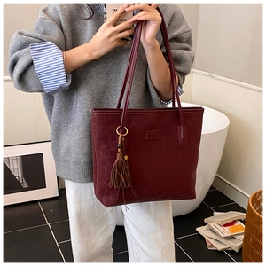 Detail of burgundy leopard embossed suede tote bag with stylish brown tassel ornament