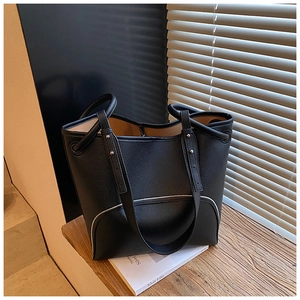 Detail of black pebbled leather bucket bag with white piping and silver rivets