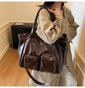 Detail of dark brown vintage faux leather tote bag with functional front zipper pockets