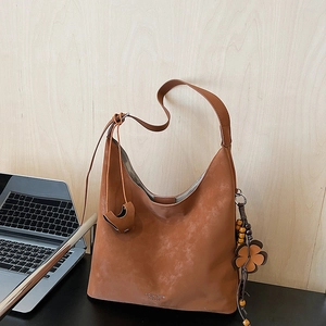 Detail view of caramel hobo bag with wood bead tassel and leather flower charm