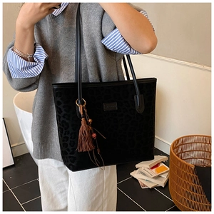 Detail of black leopard print tote bag with leather tassel and long shoulder straps