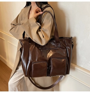 Detail of a large vintage brown tote bag with three front zippers and long shoulder strap