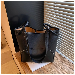Detail of black pebbled leather tote bag featuring silver studs and large capacity