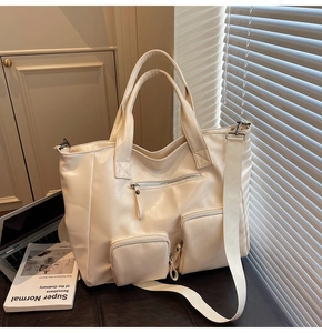 Detail of beige large capacity tote bag with multi-pockets and wide woven shoulder strap