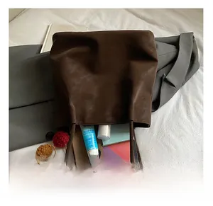 Detail showing high-capacity interior of dark brown suede tote bag with daily items