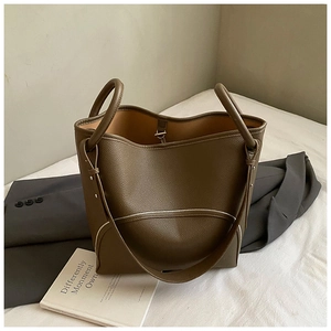 Detailed close-up of dark brown pebble leather texture on a spacious bucket bag
