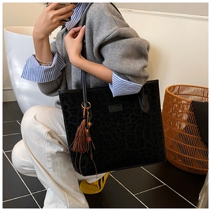Detailed view of leopard print tote bag with stylish brown tassel and leather straps