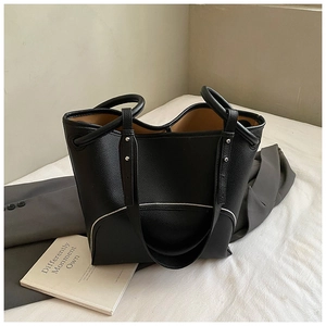 Detailed view of black lychee-grain tote bag featuring white stitching and premium texture