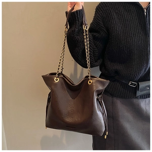 Detail of dark brown leather tote bag with gold chain strap and drawstring accents