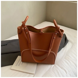 Macro detail of brown pebble leather tote bag with white piping and sturdy wide straps