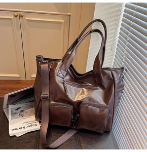 Detail view of large dark brown leather tote bag with multi-zipper pockets and wide strap