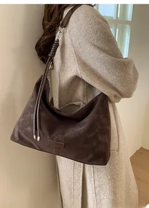 Détail du sac hobo en daim marron foncé avec bandoulière tressée et finition mate élégante