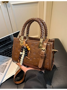 Vintage brown embossed handbag with woven handle and cute bear patterns on a desk