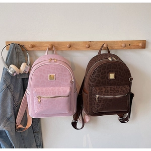 Détail de sacs à dos en cuir léopard avec fermetures dorées et poches multiples