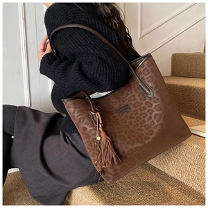Detailed close-up of a leopard print tote bag with fringe charm and premium PU leather texture