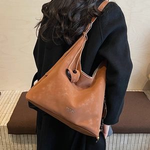 Macro view of vintage brown suede shoulder bag featuring minimalist brand logo detail