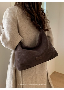 Détail du sac fourre-tout en daim mat marron foncé avec une ambiance rétro minimaliste