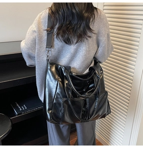 Detail of black glossy PU leather tote bag with dual zipper pockets and nylon strap