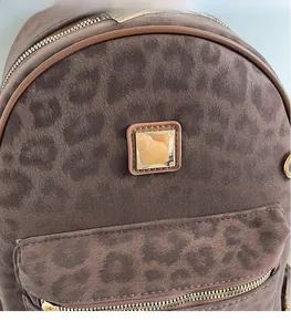Détail du sac à dos en daim léopard avec emblème en métal doré et coutures précises