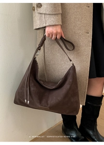 Détail du sac hobo en cuir mat marron foncé avec bandoulière nouée et design spacieux