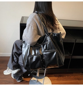 Detail of black washed leather tote bag showing spacious pockets and adjustable shoulder strap