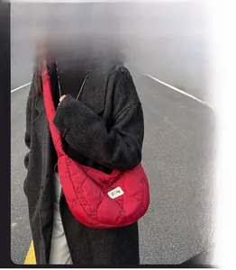 Street style shot of a red quilted dumpling crossbody bag with heart patterns