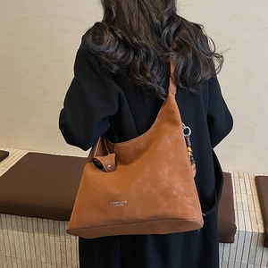 Detail of caramel suede hobo bag with white logo lettering and beaded accessories