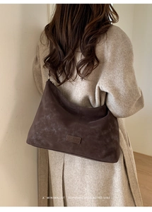 Détail macro de couture verticale et étiquette en cuir sur un sac hobo marron foncé