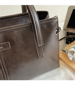 Close-up of deep brown leather shoulder bag with fine stitching and silver eyelet details
