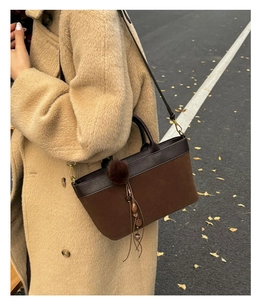 Dettaglio della borsa tote marrone scuro in pelle scamosciata con ciondolo in legno